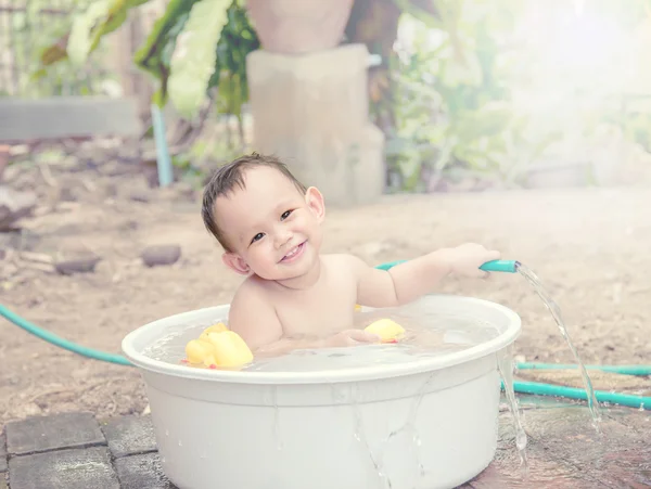 Baby bathing out door, baby hand holding the hose which water f — стоковое фото