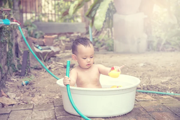 Bebê tomando banho fora da porta, mão do bebê segurando a mangueira que água f — Fotografia de Stock