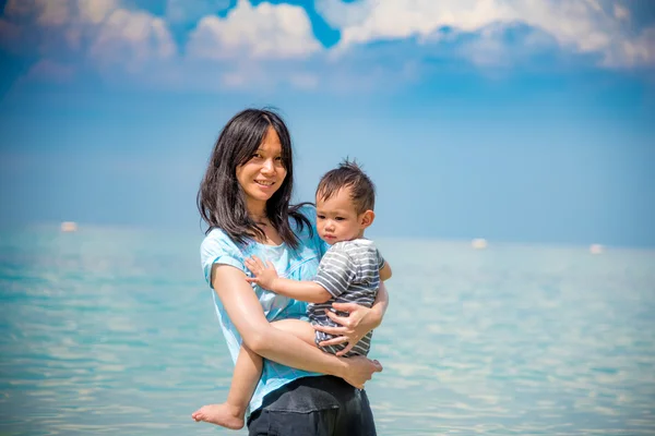 Genç Asyalı anne holding bebek sahilde — Stok fotoğraf