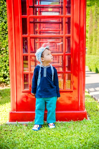 Ritratto di asiatico bambino ragazzo stand accanto di rosso telefono cabina — Foto Stock