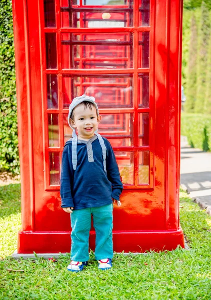 Ritratto di asiatico bambino ragazzo stand accanto di rosso telefono cabina — Foto Stock