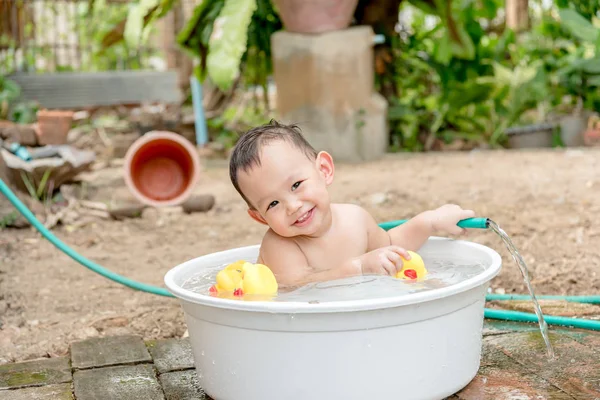 Top view Asian baby boy outdoor bathing in the white bathtub. H — стоковое фото