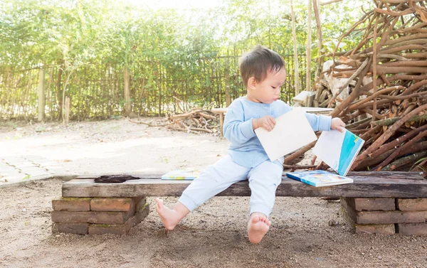 Asijské chlapeček čtení příběh knihy, chlapče opotřebení červená bota sedí na — Stock fotografie