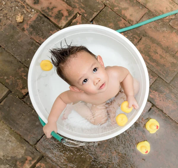 Top view Asian baby boy outdoor bathing in the white bathtub. H — стоковое фото