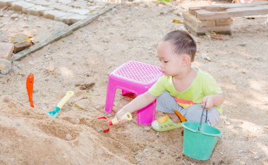 Tay bebek çocuk palying oyuncak ile kum yığını üzerinde  