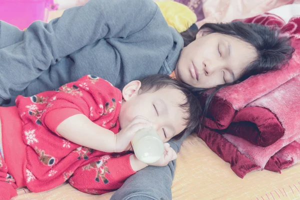 Mama asiatică ține copilul la braț în timp ce copilul bea lapte din sticlă în timp ce doarme — Fotografie, imagine de stoc