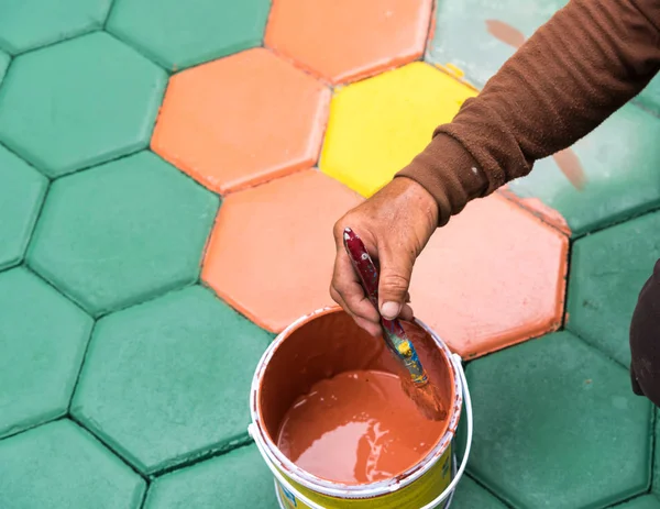 El trabajador de mampostería pintando bloque de pavimentación por cepillo de aire de color y —  Fotos de Stock