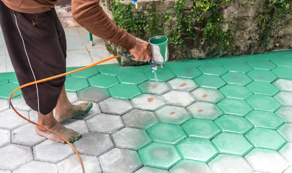 El trabajador de mampostería pintando bloque de pavimentación por cepillo de aire de color y —  Fotos de Stock