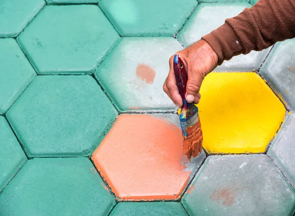 El trabajador de mampostería pintando bloque de pavimentación por cepillo de aire de color y — Foto de Stock