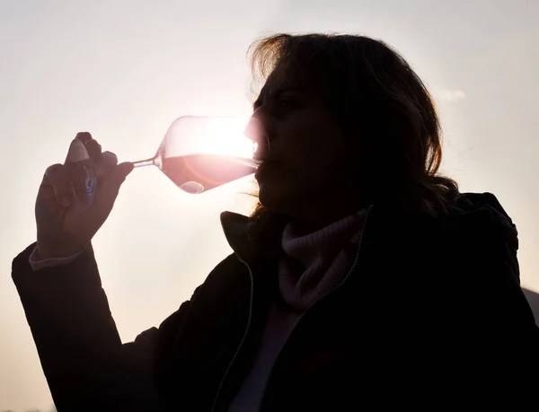 Mujer degustando vino blanco bajo las luces del atardecer. Imagen en color — Foto de Stock