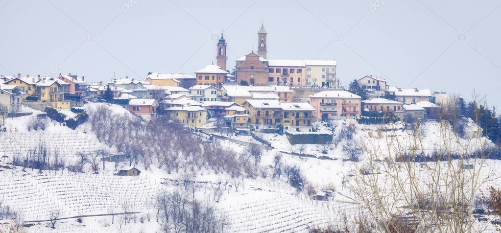 Winter panoramic view of the hilly region of Langhe (in the southern area of Piemonte Region, Northern Italy), with a typical medieval village (Cuneo Province), world famous for its valuable wines like red wines Barolo and Barbaresco.