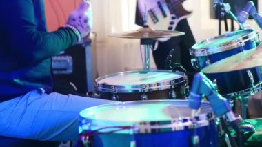 Konserde oyun davul el sopalar yavaş kapatın. Canlı grup ve gitar çalar arka plan renkli neon ışığı ile gece kulübü Festivali aşamada performans sopa ile davul çalmayı hiçbir yüz müzisyen