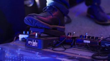 Pedal kurulu yakın basarak. Müzisyen çocuk üzerinde etkileri pedal canlı konser yavaş hareket, adım ayakkabı ayağından. Adam elektro gitar oyuncu düz pedalboard Reverb veya gecikme müzik efekti yapma basarak