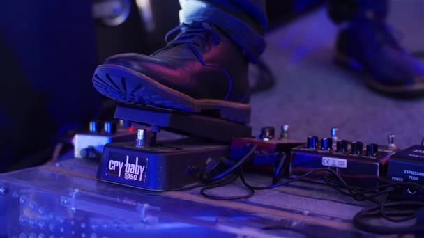 Pedalera presionando de cerca. Pie de niño músico en zapato pisando el pedal de efectos en concierto en vivo en cámara lenta. Hombre guitarrista eléctrico presionando pedalera plana haciendo reverberación o retrasar el efecto de la música — Vídeo de stock