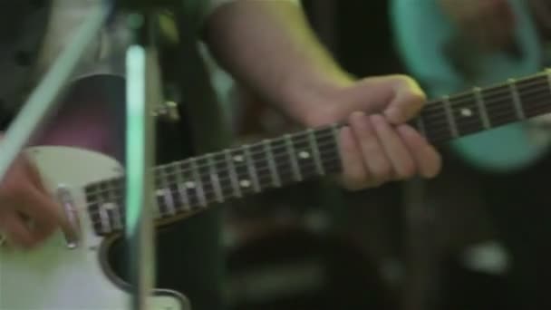 Naciśnięcie akordy gitara gra szczegół ręce płytkiej głębi pola. Gitarzysta palców trzymaj notatki gryźć deska gitara. Muzyk wykonuje solo na koncert rockowy w klub nocny. Koncert boys band balu — Wideo stockowe