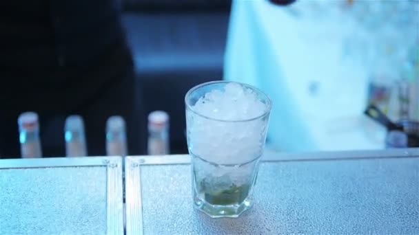 Заставить алкогольный коктейль наливать сироп в стекло со льдом замедленным движением. Бармен добавляет ягоды или фруктовый ликер в бокал с напитком мохито в ночном клубе — стоковое видео