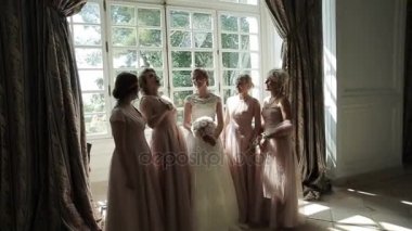 Nedime gelin yavaş hareket mutlu gülüyor. Güzel kız eğlenceli ve güneş ışık odada konuşuyor çevresinde gelinin poz. Bekarlığa veda partisi duygusal. Şık düğün elbise moda stil