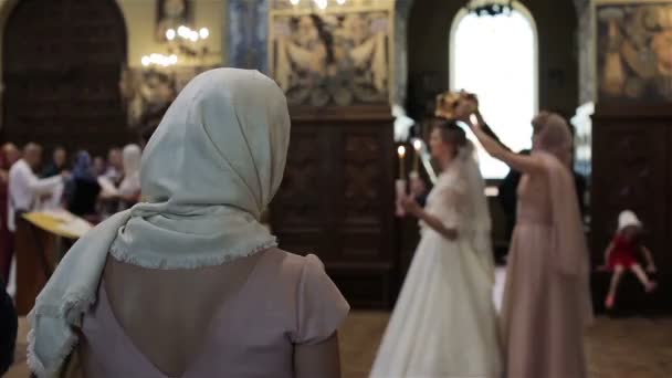 In de kerk orthodoxe vrouw steken zegen zichzelf met de vingers en boog huwelijksceremonie uitzicht vanaf terug kijken. Grieks-orthodoxe kerk rituelen tradities douane. Religieuze mensen cult aanbidding concept — Stockvideo