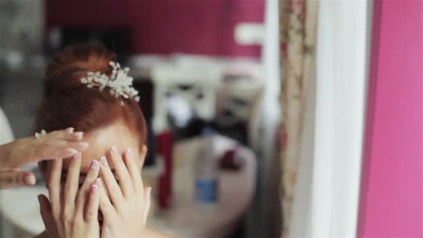 Женщина закрывает лицо руками, защищающими от лака для волос. Парикмахер, использующий лак для волос, чтобы исправить элегантную прическу в салоне красоты — стоковое видео