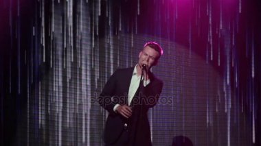 Adamım söylüyor mikrofon stand aşamada kapatın. Şık yakışıklı şarkıcı ışık Led ekran arka plan yavaş yavaş düşüyor, soyut animasyon gösterilen, yüzündeki duyguları şarkıyla gerçekleştirir yağmur satırları 