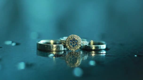 Wedding rings illuminated with artificial source of light from top studio macro close up shallow dof. Jewelry design - engagement ring together with bride and grooms shine lying on reflecting surface — Stock Video