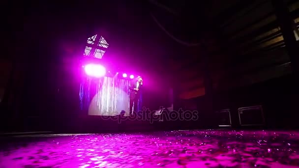 Silhouetted hombre canta en la luz decorada piso de escenario concierto POV ángulo bajo. Cantante realiza la canción con el soporte del micrófono en la animación abstracta del fondo de la pantalla led de Año Nuevo que cae lentamente copos de nieve — Vídeos de Stock