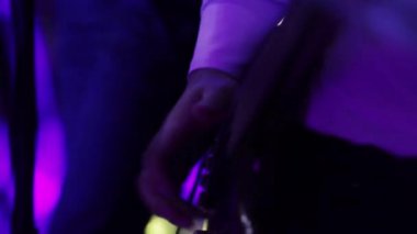 Gitar bas yakın çekim mavi neon ışık oynuyor. Tarzı gitar sahne performansı tokat. Gitarist parmakları hızlı tıngırdatma ve elektro gitar koparmak. Gece kulübü konser sığ derinlik-in tarla solo performans