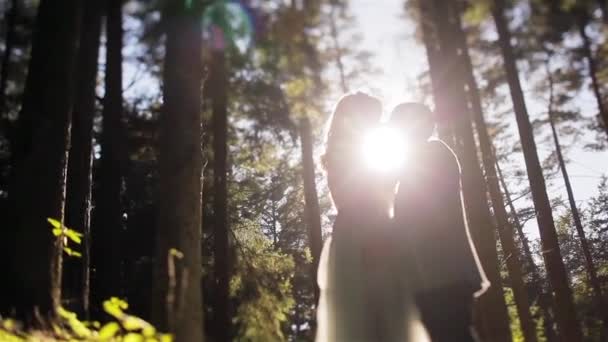 Чоловік і жінка в лісі стоять затінені разом, приймаючи і цілуючи зворотний зв'язок з сяючим вечірнім нахилом сонця крупним планом. Весільна мода на природі. Ніжність єдність концепція любові мрії — стокове відео