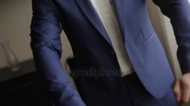 Mavi takım elbise ceketi kadar düğmelerini hiçbir yüz yakın çekim 4 k giyinmiş adam. Şık giyimli adamla kontrol uzunluğu hortumlar ve dışarı çıkmak hazırlanıyor uygun ceket düğmeleri takılır 
