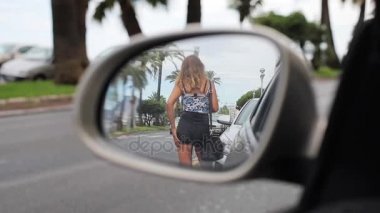 Geri kanat fender aynada bir araba sokak yol yansıması üzerinde duran genç seksi kadın. Şortla ince kız yan ayna tarafından geçen otomobil ile ilgilendiğin sürücü baştan onun kalça dokunur