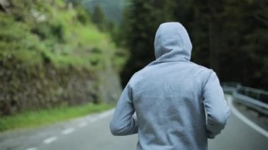 Adam dağ yolda hiçbir yüz geri koşu yavaş kapatın. Yalnız atlet açık havada içinde gri kapşonlu kazak sabah. Spor adam egzersiz sprint ve eğitim doğada çalışıyor. Özgürlük ve seçim