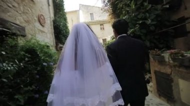 Yeni nikahlı çift gelin ve damat geri meçhul eski şehrin dar sokak yavaş yürü. Kadın beyaz elbise ve peçe ve siyahlı adam el ele tutuşsun İtalya veya Fransa Avrupa birlikte kiliseye gitmek