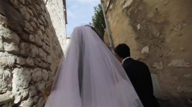 Yeni evli karı koca tanınmaz evli ağır çekim almak için eski İtalyan kasabasının dar sokakta yürümek. Genç aile gelin peçe tutuşup kocası ile çırpınan ile geleceğe gitmek