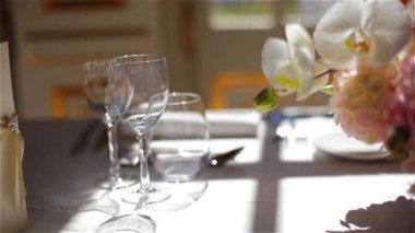 Menü carte gözlük şarap su ve pembe çiçekler buket üzerinde makro yakın çekim izleme iyi yemek için düzenlenmiş beyaz masa örtüsü için boş. Şenlikli şık masa Restoran Cafe ziyafette yemek için ayarla