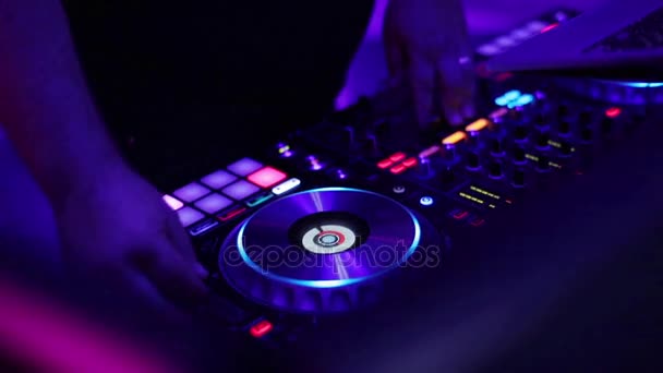 DJ παίζουν μίγμα μουσικής πικάπ κατάστρωμα με χρώματα φωτός χέρια κοντινό σε αργή κίνηση. Πόμολα στροφή δάχτυλο πιέστε μαξιλάρια στο midi ελεγκτή πλέγμα επαγγελματική λειτουργία κονσόλας launchpad αναζήτησης κομμάτι μίκτη σε φορητό υπολογιστή — Αρχείο Βίντεο