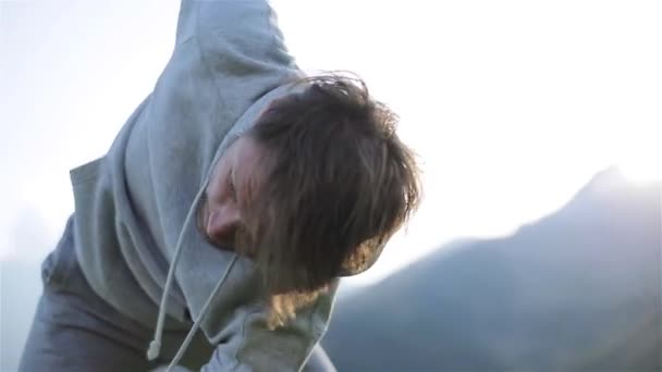 El hombre hace ejercicio matutino pies que tocan la cruz manos giratorias se calientan al aire libre cerca de cámara lenta sol brillo. Entrenamiento de pie sobre el fondo de la montaña. Estilo de vida saludable voluntad poder motivación concepto — Vídeos de Stock