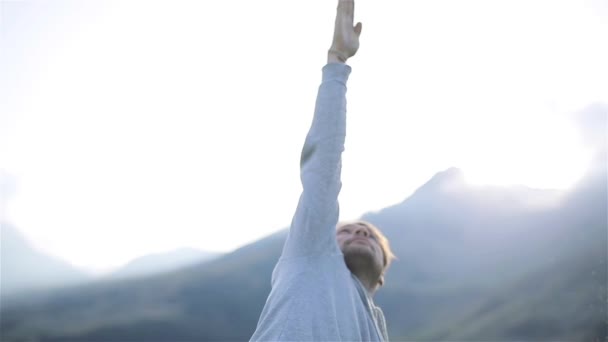 Homem de ioga estendendo a mão acima montanhas natureza perto sol brilho. Em pé em asana olhando para cima exercício ao ar livre na manhã ensolarada ou à noite. Treinamento de estilo de vida saudável trabalhando fora conceito sportswear masculino — Vídeo de Stock