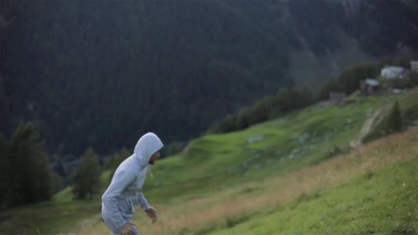 Ember jogs fut fel hegyi hill arcát közelről lassított. Csuklyás runner kocogó Sprint erőfeszítés vonatok maratont szabadban, a fű, a friss levegő szürke sportruházat cipők. Sport egészséges életmód — Stock videók