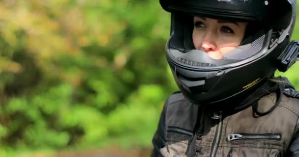 オープン間近のバイクで女性心配してグリーンを探してヘルメット デフォーカス背景 オートバイが反転停止保護シールドに女の子バイカー座ってが乗る休憩に行く準備ができて後大きく息します — ストック動画