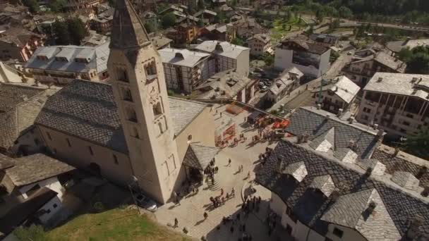 4 k góry Aerial strzał starych Włochy europejskiego centrum Courmayeur z placu i dzwonnicy Kościoła w słoneczny dzień. Niedziela życie małej wiosce w górach Alpach doliny Aosty. Zwiedzanie atrakcji turystycznych — Wideo stockowe