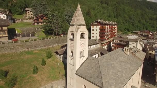 Aerial shot of old belfry with bell ringing alarm over medieval European town in Alps valley Italy. 4k copter close flight around St. Pantaleon Church clock tower. Medieval history historic heritage — Stock Video