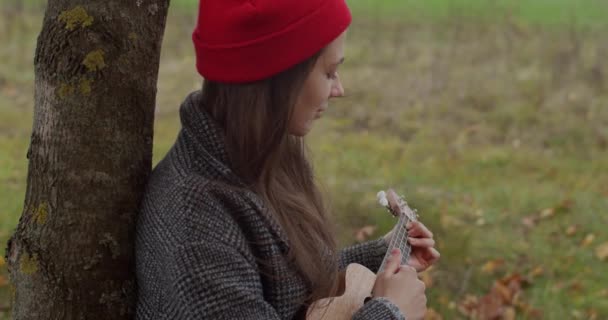 Ευτυχισμένη Γυναίκα Μουσικός Παίζει Γιουκαλίλι Κάθεται Κάτω Από Δέντρο Χαλαρωτική — Αρχείο Βίντεο