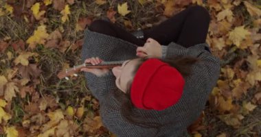 Neşeli kız dışarıda oturmuş Hawaii gitarını yavaş çekimde çalıyor. Ukulele enstrümanıyla eğlenen çekici bir kadın manzarası. Hobisiz hippi yaşam tarzı