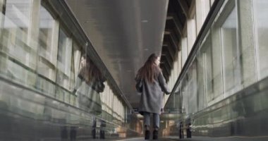 Yürüyen yolda duran genç bir kadın ağır çekimde portre. Dişi gezgin, yolcu aracına binip, kapalı alandaki doğal ışığa doğru yola koyuluyor. Seyahat iş seyahatleri konsepti