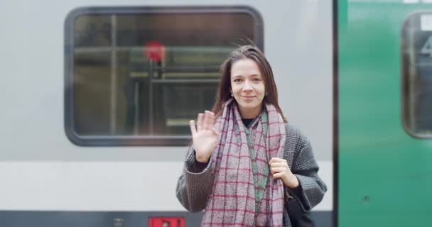 年轻女子在火车站挥手道别后离开户外慢镜头的正面肖像 长发女孩看着镜头认真准备上火车 交通旅游概念 — 图库视频影像