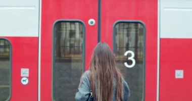 Bir kadının treni tren peronunda ağır çekimde yakaladığı arka plan görüntüsü. Esmer kız gezgin, arabaya binip tatile çıkıyor. Ulaşım kentsel yaşam tarzı değiştiriliyor