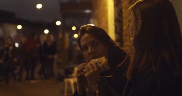 Dos Chicas Hambrientas Comiendo Bocadillos Comida Rápida Sentadas Calle Ciudad — Vídeo de stock