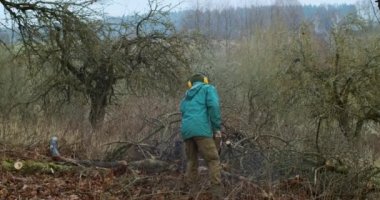 Keresteci adam, sonbaharda kırsal alanda odun keserek araziyi yavaş çekimde temizliyor. Elinde testereyle dışarıda çalışan genç bir işçi. Ağaç kesme endüstrisi profesyonel mesleği kütük kesme