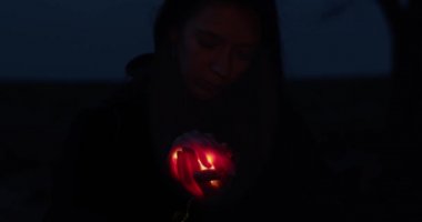 Avuç içlerinin içinde parlayan ışığı tutan gülümseyen kızın karanlık portresi. Güzel bir kadın ışıltıyı koruyor fotokopi çekimini yavaşlatıyor. Din Noel konsepti