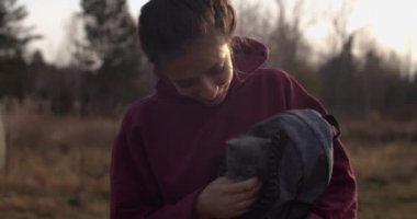 Sevimli kedi yavrusunu elinde tutan çekici kız kameraya mutlu bir şekilde gülümsüyor kırsal alanda. Kırsal alanda aşk dolu gri kediyi okşayan genç bir kadın. Kedi besleme koruma programı